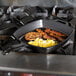 A Lodge square cast iron skillet with eggs and bacon cooking on top of a stove.