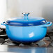 A Caribbean blue Lodge enameled cast iron Dutch oven on a stove.
