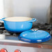 A Caribbean blue Lodge enameled cast iron Dutch oven on a stove.