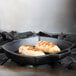 A Lodge cast iron square grill pan with two chicken breasts cooking in it.