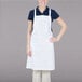 A woman wearing a white Chef Revival bib apron with one pocket.