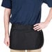 A man wearing a black Chef Revival waist apron with pockets.