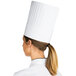 A woman wearing a Chef Revival pleated paper chef hat.