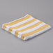 A folded yellow and white striped Oxford pool towel.