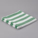 A folded green and white striped Oxford pool towel.