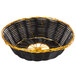 A black and gold round rattan basket with a handle.