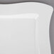 A close up of a white Fineline square plastic plate with a curved edge.
