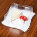 A slice of cheesecake sits in a Fineline plastic container.