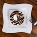A Fineline white plastic square plate with a chocolate dessert and a white swirl on top served with a fork.