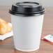 A white Sabert paper hot cup with a black lid.