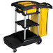 A Rubbermaid janitor cart with a yellow bag on it.