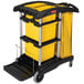 A black Rubbermaid janitor cart with yellow bins on the bottom.