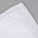 A white Oxford Regale bath towel with dobby border and hem on a gray surface.