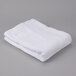 A folded white Oxford Regale bath towel on a gray surface.