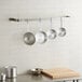 A Regency stainless steel wall mounted pot rack with pans on it.