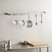 A kitchen with a Regency stainless steel wall mounted pot rack holding pots and pans.