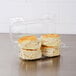 A Dart clear plastic container with a high dome lid holding four biscuits.