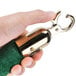 A hand holding a green and gold Aarco rope with brass ends.