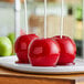 Three red apples coated with Great Western Applicious Candy Apple Coating on a white plate.