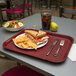 A Carlisle burgundy plastic fast food tray with a sandwich, chips, and a drink on it.