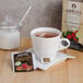 A cup of Bromley Exotic Sun Sweetened Raspberry Herbal Tea with a tea bag in it.
