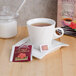 A cup of Bromley Exotic Tropical China Black Tea with a tea bag on a saucer next to a box of tea.