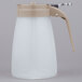 A white plastic Tablecraft syrup dispenser with a brown handle.