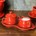 A red Fiesta sugar and creamer tray set on a wooden surface.