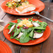 A Fiesta® luncheon plate with salad and salmon on a table with a fork.
