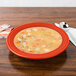 A Fiesta China rim soup bowl filled with soup on a table with a spoon.