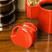 A red disc creamer pitcher on a table.
