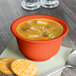 A Fiesta china bouillon bowl filled with soup and crackers on a table.