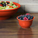 A Fiesta bouillon bowl filled with blueberries and raspberries on a table with a bowl of fruit.