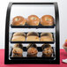 A Cal-Mil bamboo bakery display case with a variety of pastries and muffins inside.