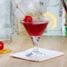 A Libbey mini martini glass with red liquid and a lemon slice on it.