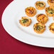 A Tuxton bright white china serving platter with mini quiches on it.