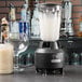 A Hamilton Beach commercial bar blender with a glass and a bottle of liquid on a counter.