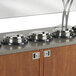 A row of Vollrath silver drop-in induction warmers on a counter top.