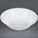 A CAC white bone china nappie dish with food inside on a gray surface.