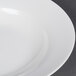 A close-up of a CAC white bone china soup bowl with a white rim.