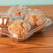 A close up of InnoPak clear plastic container with four muffins inside.
