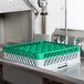 A grey and green plastic Noble Products glass rack in a sink.