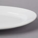 A close-up of a CAC Harmony white porcelain platter with a rim.