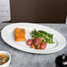 A CAC Harmony super white porcelain platter with food on a table.