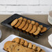 A black rectangular Milano plate with a group of cookies on it.