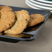 A table with a rectangular black Milano plate filled with cookies.