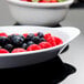 A white oval side dish filled with strawberries, raspberries, and blueberries.