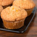 A group of muffins on a black Sabert catering tray.