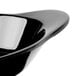 A close-up of a black oval side dish with a curved edge.