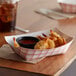 A red check paper food tray with fried shrimp and sauce on a table.